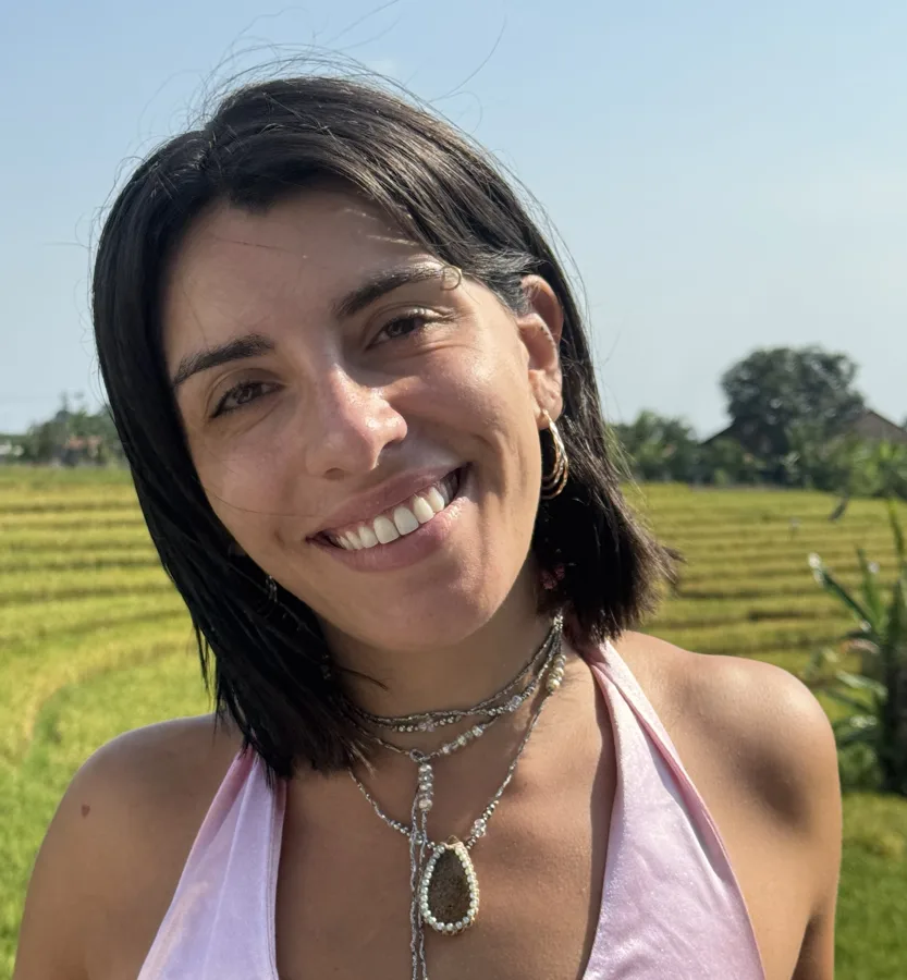 Pamela Contreras smiling in a rice field in Bali, wearing a Rosix amulet.